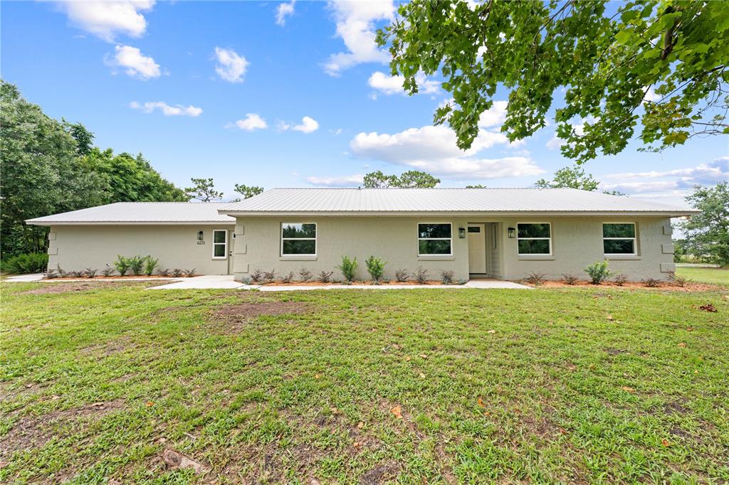 A single-story house with a light-colored stucco exterior and a metal roof — 4279 HENRY J AVE, ST CLOUD, FL