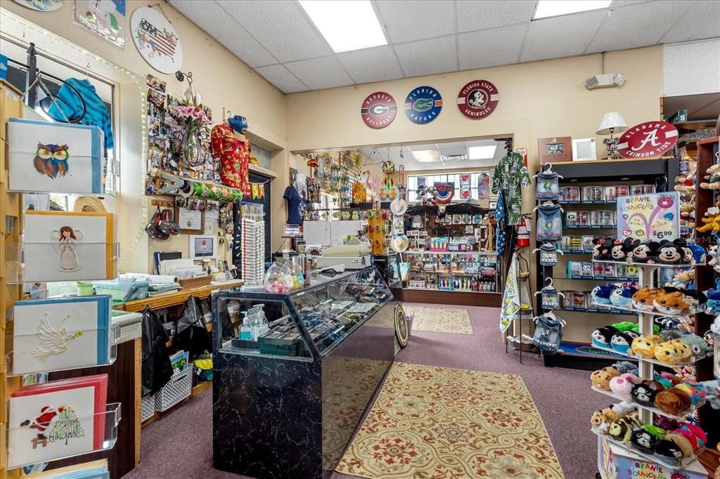 A retail shop interior features a glass display counter, shelves of merchandise, and sports memorabilia — 317 N DONNELLY, MOUNT DORA, FL