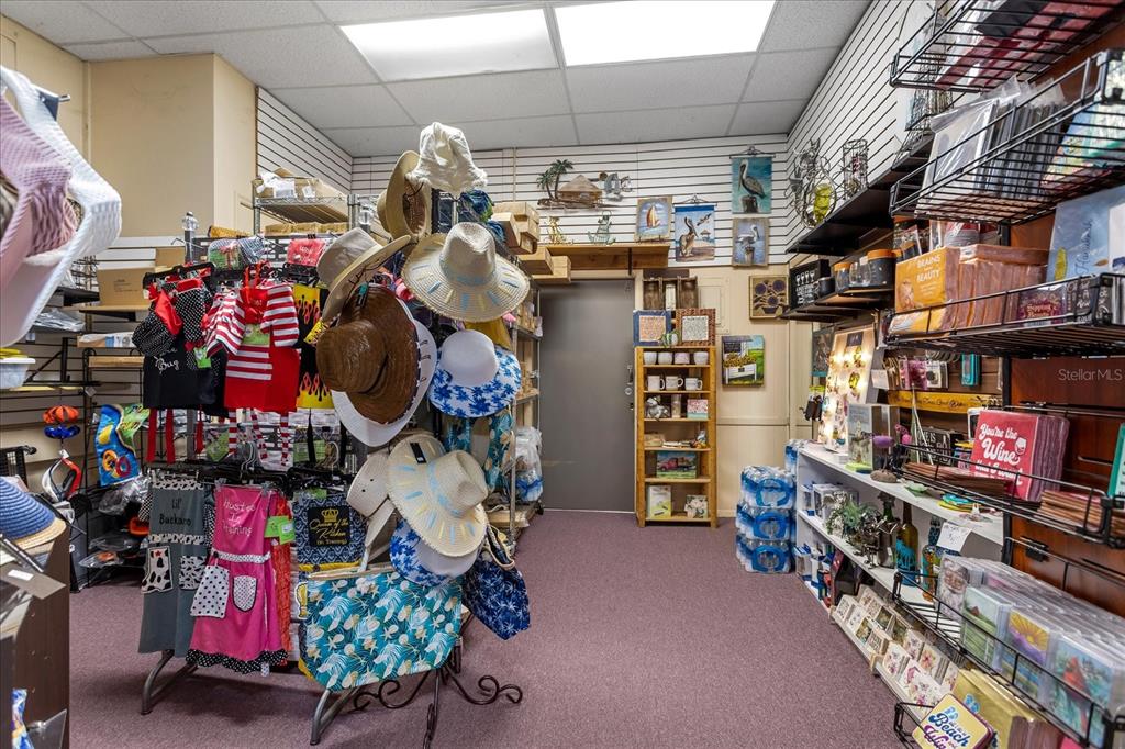 A retail shop interior features clothing, hats, and various gift items on display shelves — 317 N DONNELLY, MOUNT DORA, FL