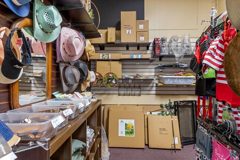 A retail storage room features shelves filled with hats, boxes, and various merchandise — 317 N DONNELLY, MOUNT DORA, FL