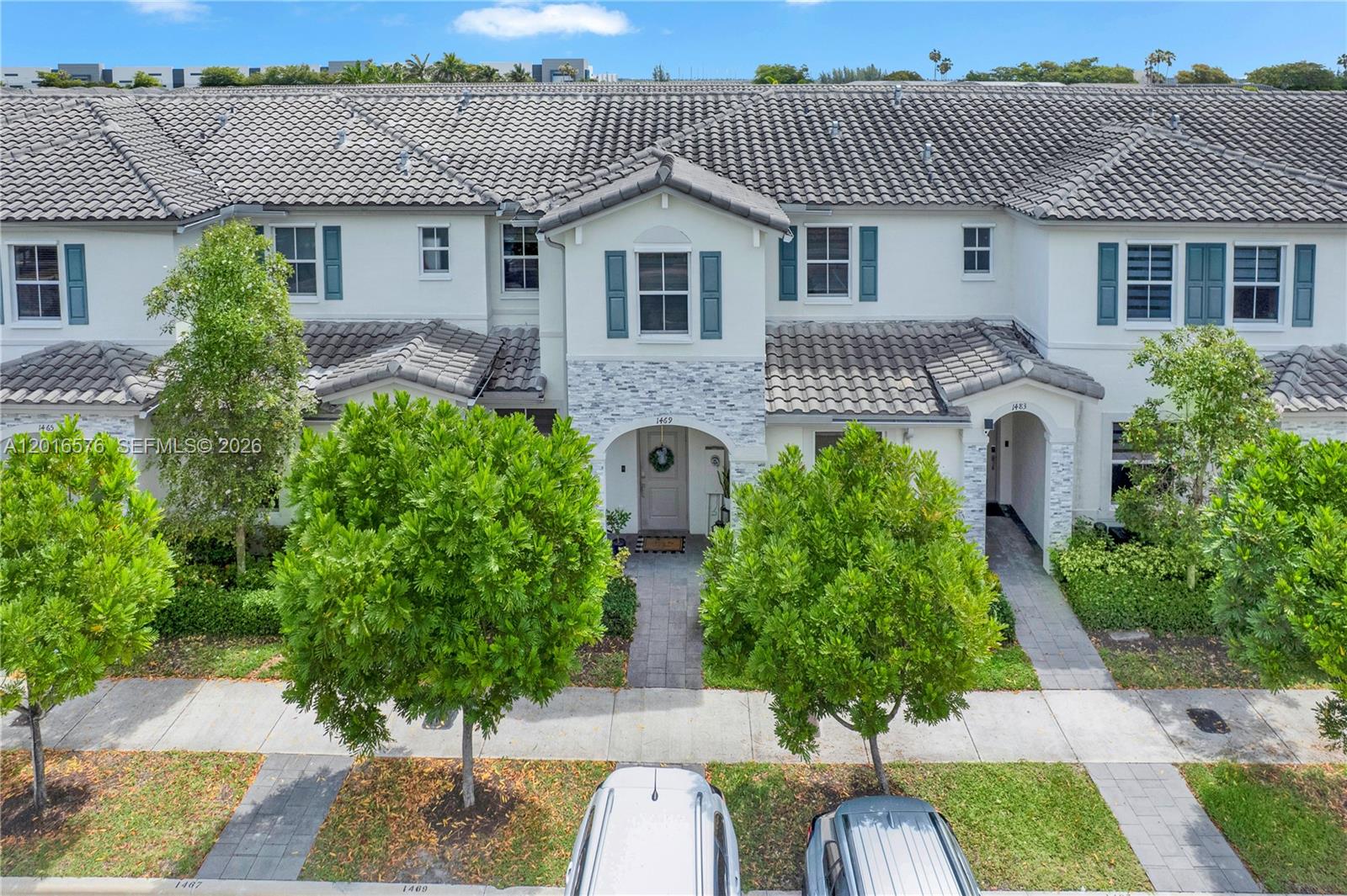 An exterior view of a multi-unit townhouse complex with gray tile roofs and stone accents — 1469 SE 26th Ter, Homestead FL 33035, HOMESTEAD, FL
