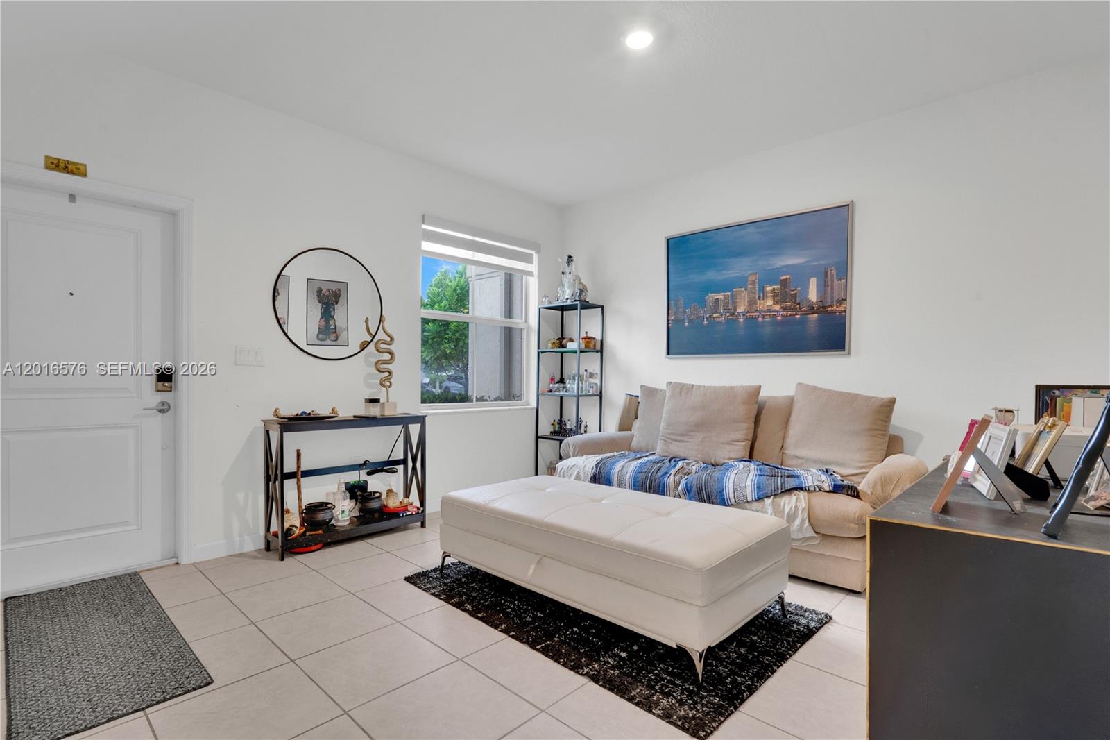 A living room features a beige sofa, white ottoman, console table, and a city skyline print — 1469 SE 26th Ter, Homestead FL 33035, HOMESTEAD, FL