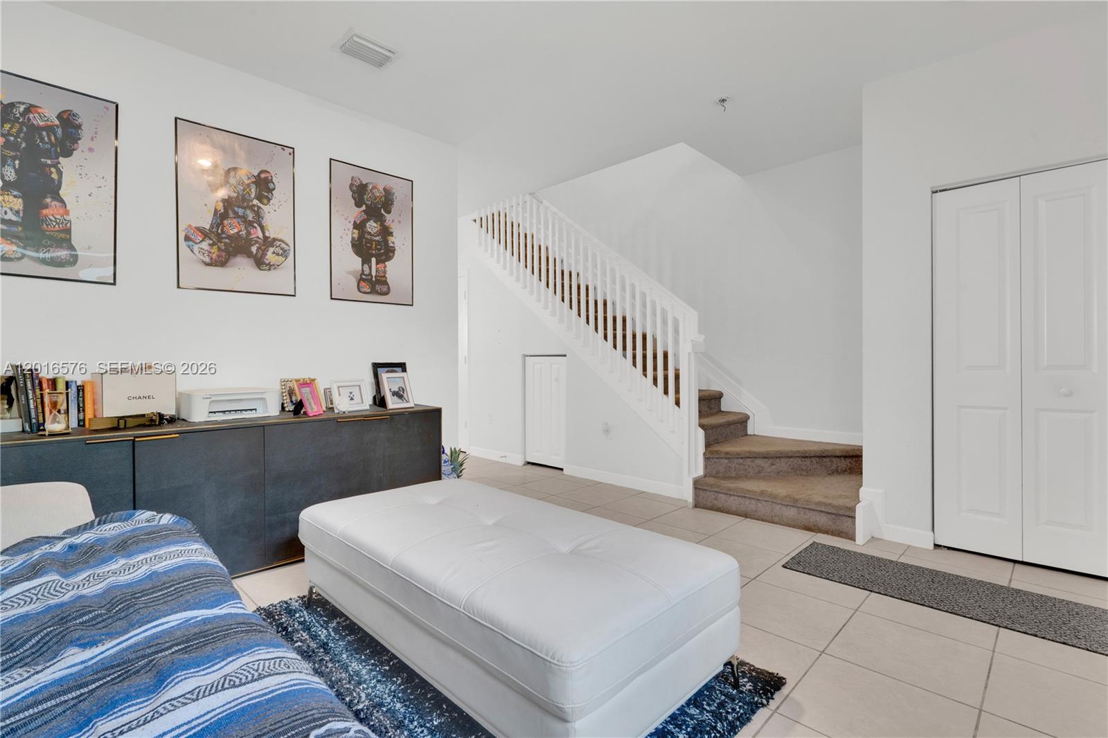 A living room features a white ottoman, a dark console table, and a carpeted staircase — 1469 SE 26th Ter, Homestead FL 33035, HOMESTEAD, FL