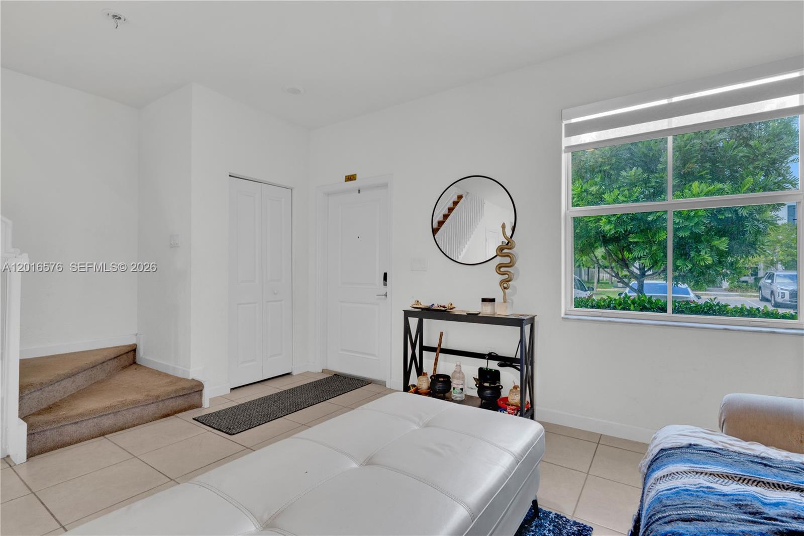 A bright entryway features tiled floors, a white door, a console table, and carpeted stairs — 1469 SE 26th Ter, Homestead FL 33035, HOMESTEAD, FL