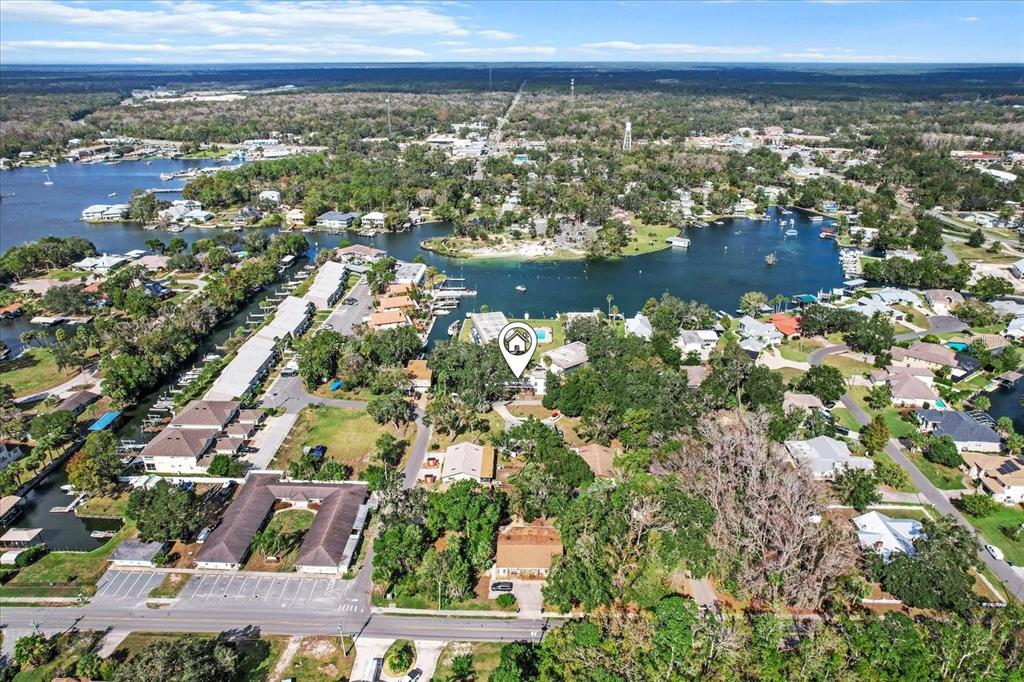 An aerial view shows a waterfront property with a pool surrounded by trees and houses — 30 SE VALARE LANE UNIT 102C, CRYSTAL RIVER, FL