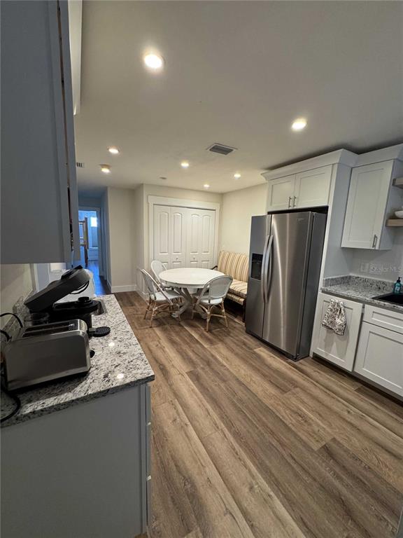 A kitchen with white cabinets, granite countertops, stainless steel appliances, and a dining nook — 30 SE VALARE LANE UNIT 102C, CRYSTAL RIVER, FL
