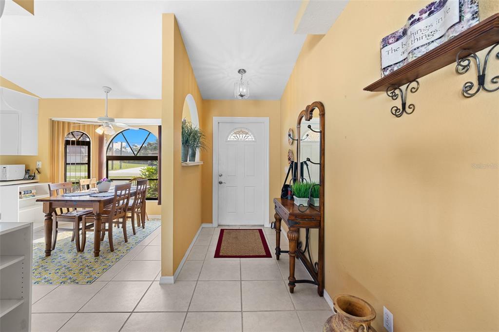 An entryway with tile flooring leads to a dining area with a wooden table — 4607 ATWATER DRIVE, NORTH PORT, FL