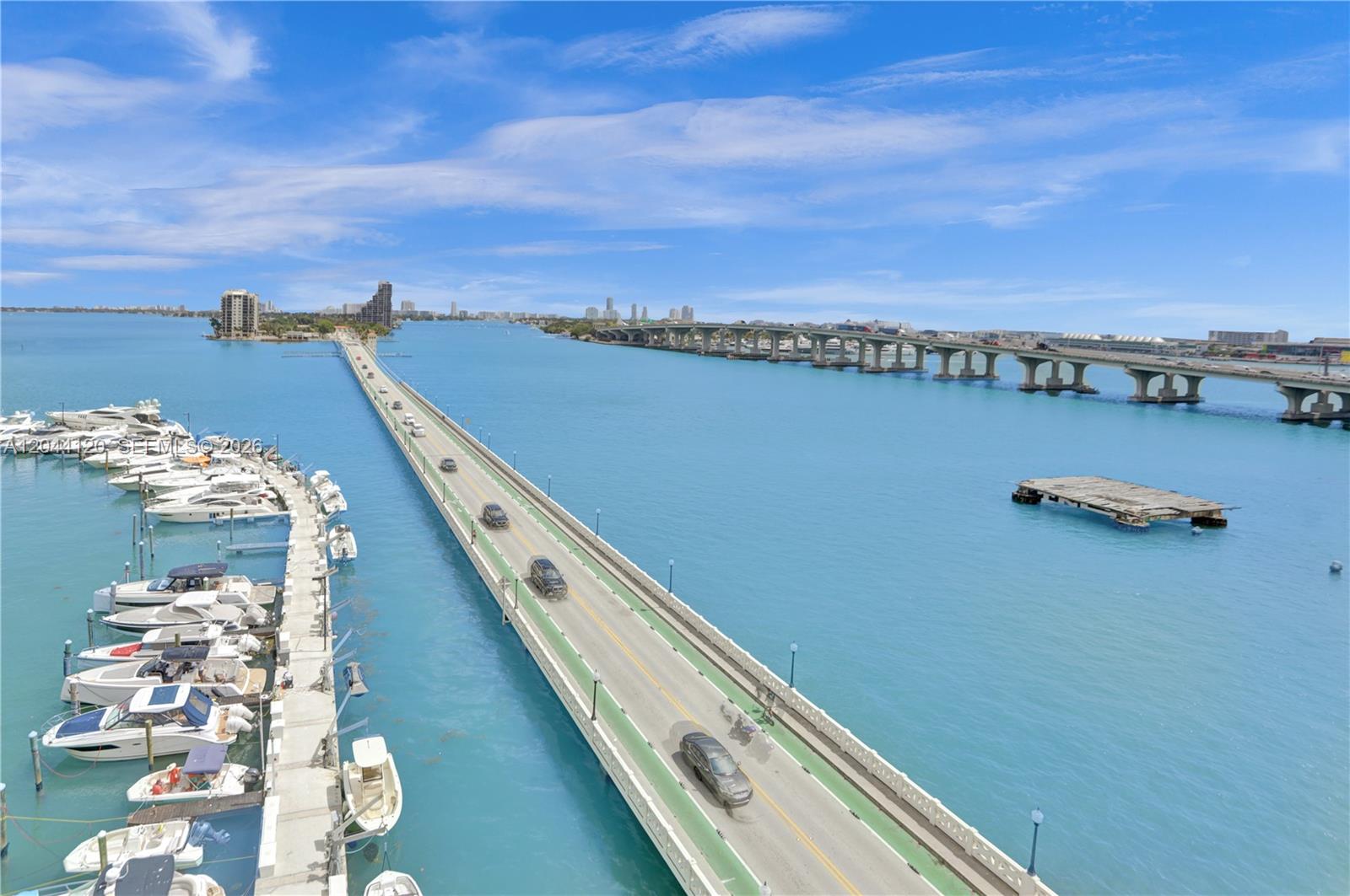 An aerial view shows a bridge over turquoise water with a marina and city skyline — 555 NE 15th St # 20I, Miami FL 33132, MIAMI, FL