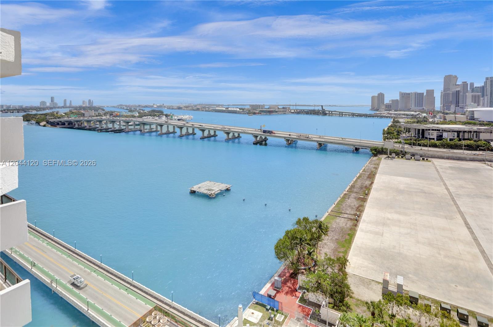 An elevated view shows a bridge spanning blue water with a city skyline beyond — 555 NE 15th St # 20I, Miami FL 33132, MIAMI, FL