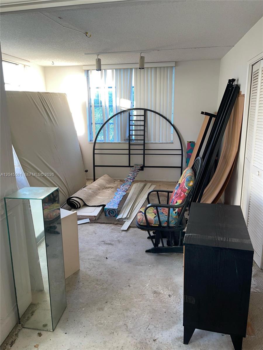 A cluttered room features a metal bed frame, a mattress, and a patterned rocking chair — 3090 N Course Dr # 401, Pompano Beach FL 33069, POMPANO BEACH, FL