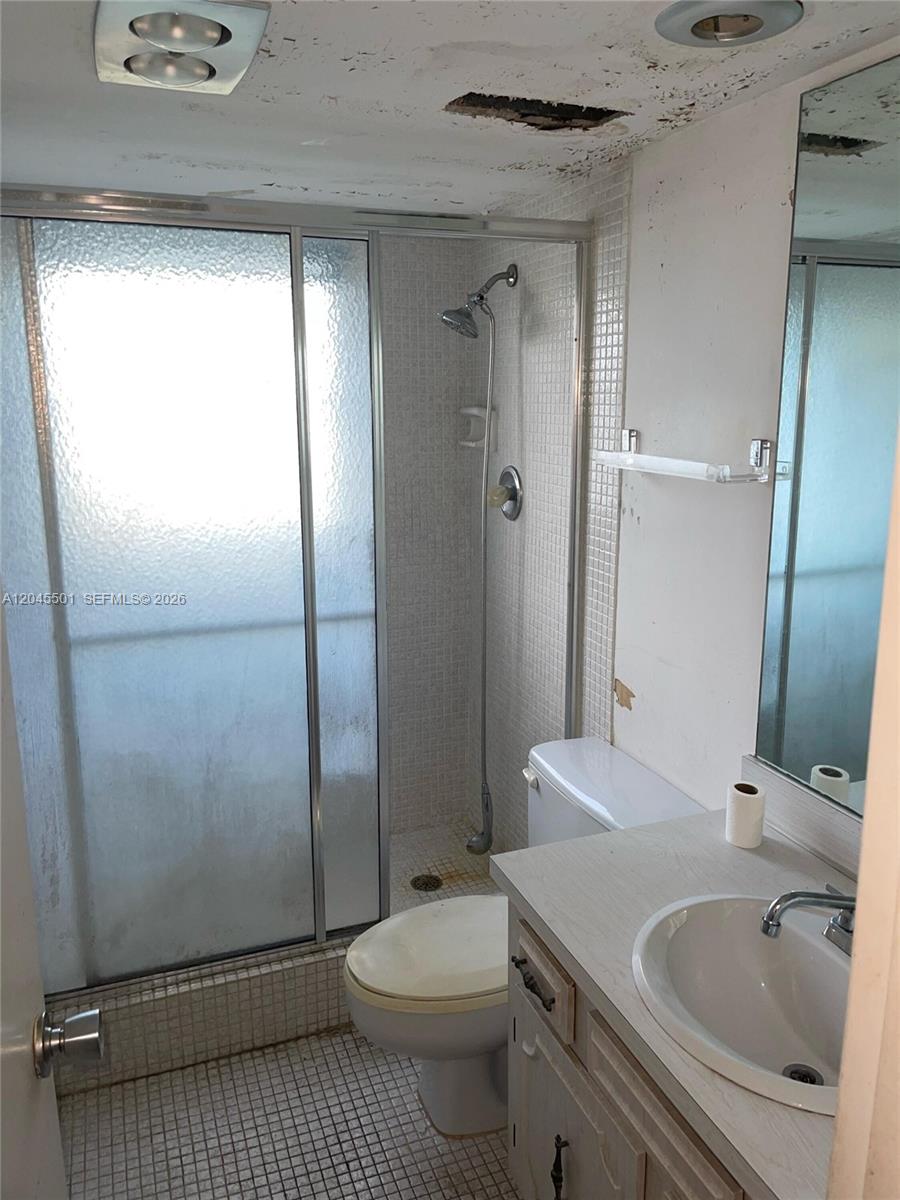 A small bathroom features a tiled shower stall, a toilet, and a vanity with sink — 3090 N Course Dr # 401, Pompano Beach FL 33069, POMPANO BEACH, FL