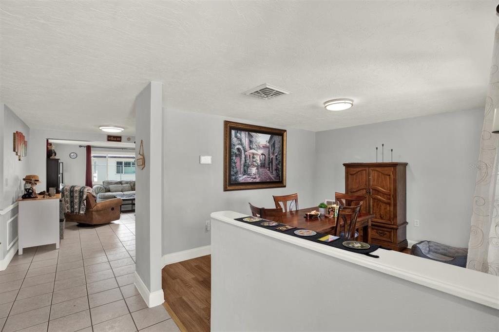 A dining area with a wooden table and hutch opens into a tiled living room — 12411 WEATHERSTONE ROW, HUDSON, FL