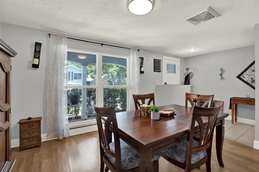 A dining room features a wooden table, chairs with patterned cushions, and a large window — 12411 WEATHERSTONE ROW, HUDSON, FL