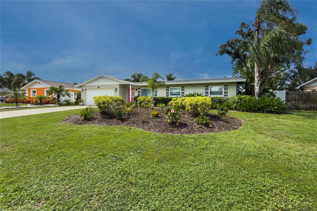 A single-story house with a tan exterior, a two-car garage, and a landscaped front yard — 3326 BOUGAINVILLEA STREET, SARASOTA, FL