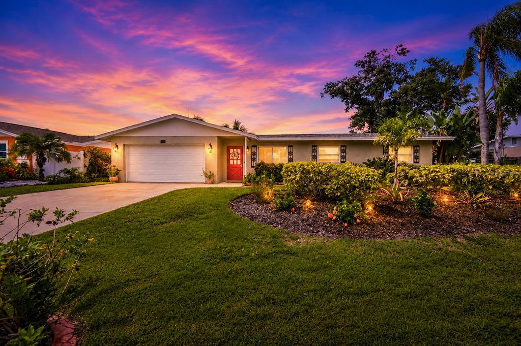 A single-story house with a white garage, red front door, and landscaped yard at sunset — 3326 BOUGAINVILLEA STREET, SARASOTA, FL