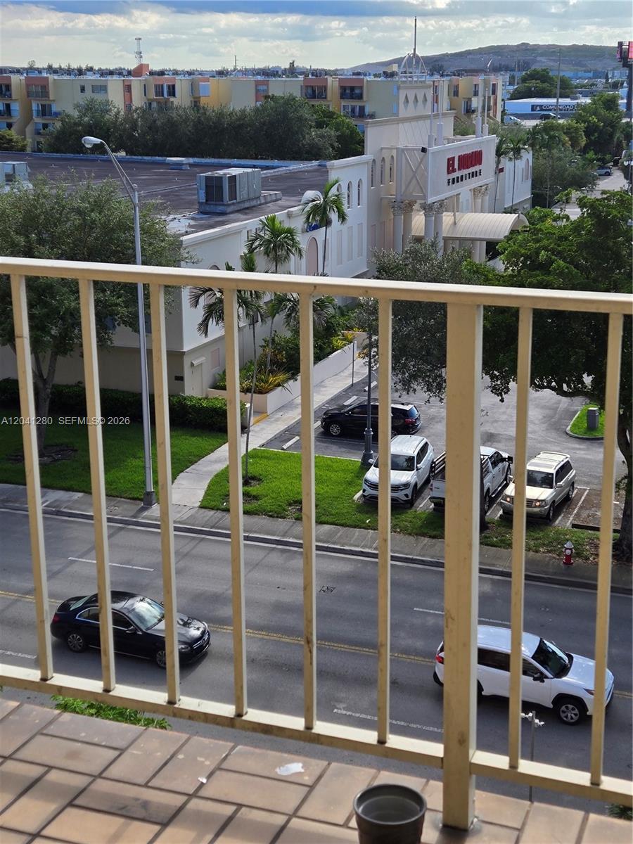 A view from a balcony overlooking a street, parking lot, and a furniture store — 4675 W 18th Ct # 606, Hialeah FL 33012, HIALEAH, FL
