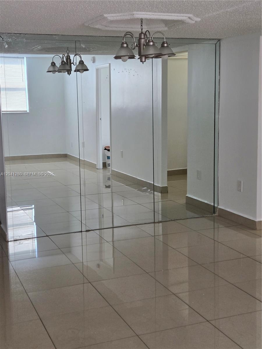 A room with tiled floors, white walls, and a large mirrored wall section — 4675 W 18th Ct # 606, Hialeah FL 33012, HIALEAH, FL