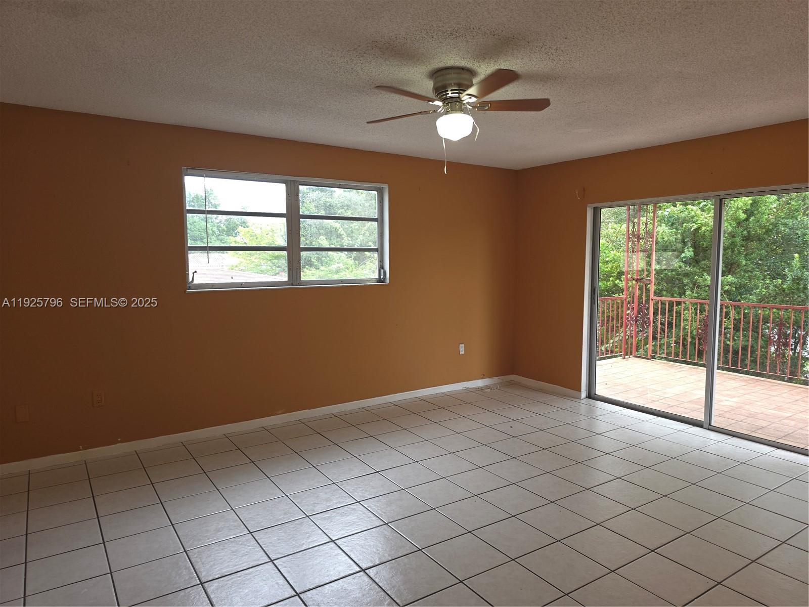 An empty room features orange walls, white tile flooring, a ceiling fan, and a balcony — 250 NW 63rd Ct # 2, Miami FL 33126, MIAMI, FL