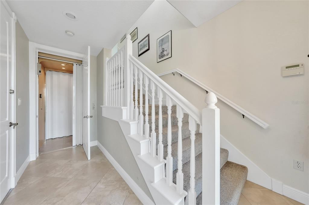 An open glass-paned front door reveals a tiled entryway with a staircase inside — 196 TARPON COVE BOULEVARD UNIT 722, PUNTA GORDA, FL
