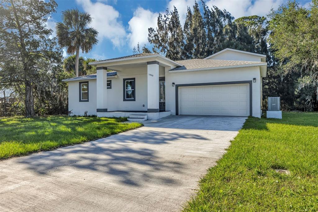 A single-story house with a white stucco exterior, a front porch, and a two-car garage — 1400 CONRAD DRIVE, NEW SMYRNA BEACH, FL