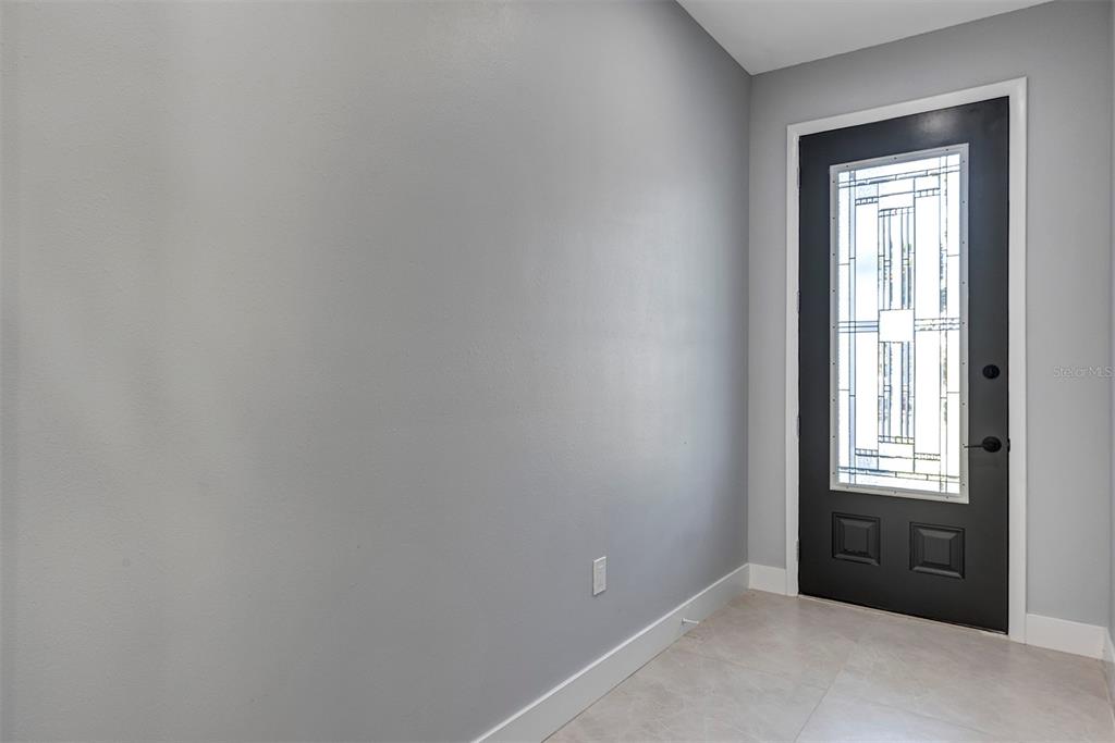 A gray-walled entryway features a black front door with a decorative glass insert — 1400 CONRAD DRIVE, NEW SMYRNA BEACH, FL