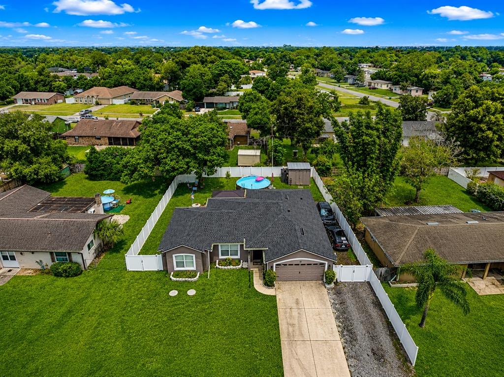 An aerial view shows a single-story house with a dark roof, pool, and fenced yard — 1214 STILLWATER AVENUE, DELTONA, FL