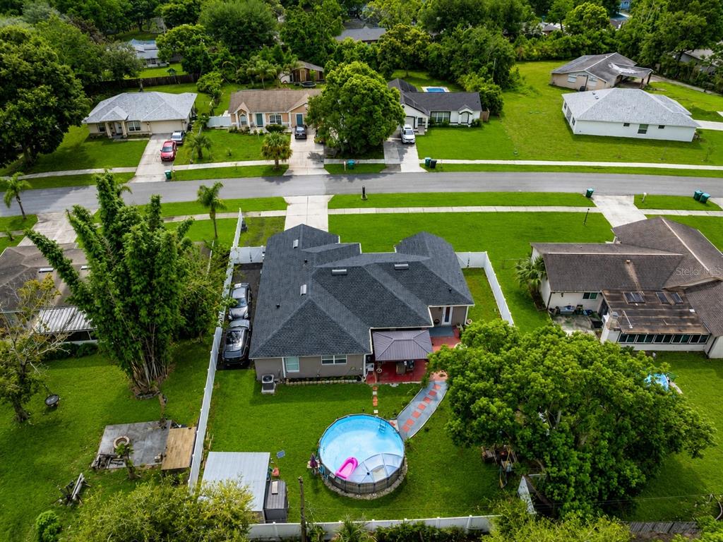 An aerial view shows a house with a dark roof, a backyard pool, and fencing — 1214 STILLWATER AVENUE, DELTONA, FL