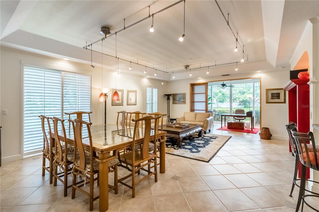 A dining area with a glass-topped table and track lighting opens into a living space — 3705 54TH DRIVE W UNIT 103, BRADENTON, FL