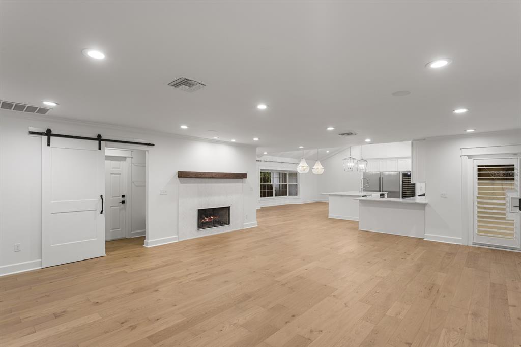 A bright, open-concept living area features light wood floors, a white fireplace, and a kitchen — 4415 W CLEAR AVENUE, TAMPA, FL