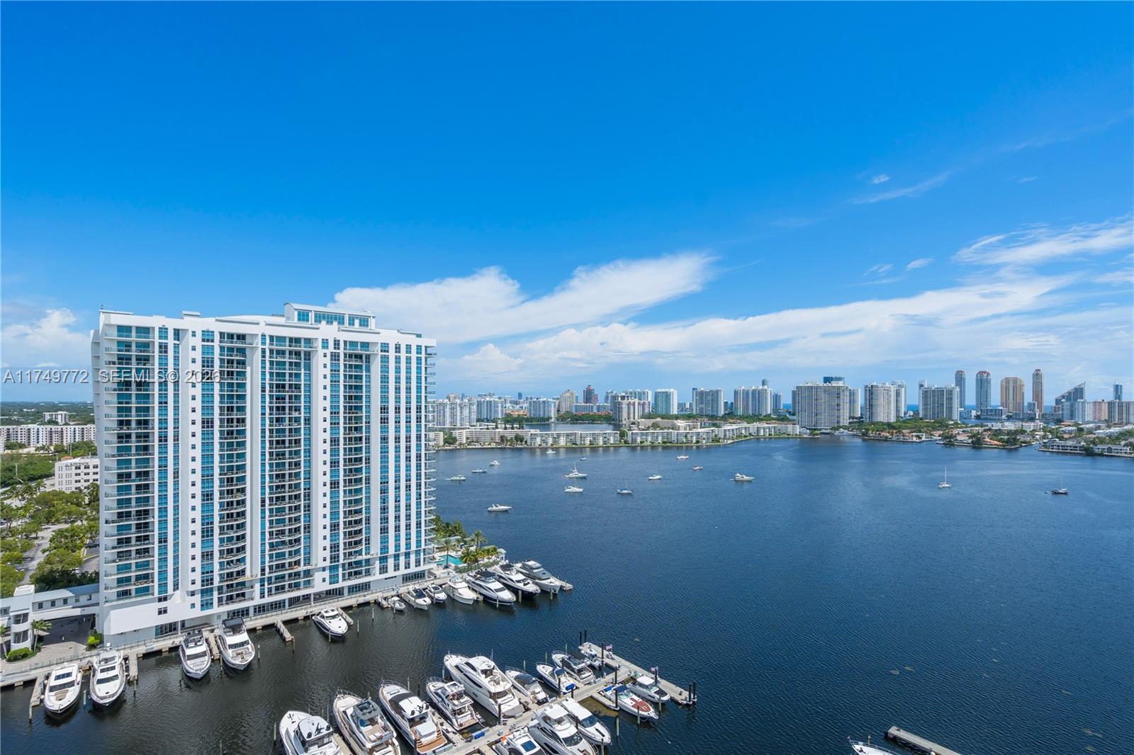 An aerial view shows a tall white apartment building next to a marina and bay — 17111 Biscayne Blvd # 2001, North Miami Beach FL 33160, NORTH MIAMI BEACH, FL