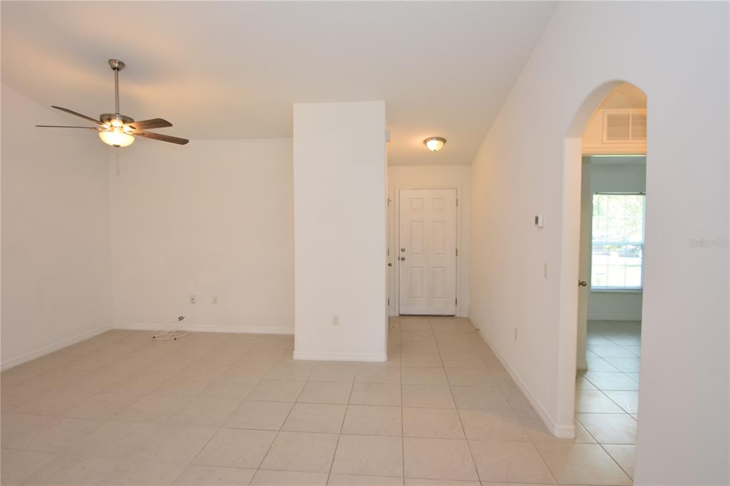 A room with light tile flooring, white walls, a ceiling fan, and an arched doorway — 77 SEA TRAIL, PALM COAST, FL