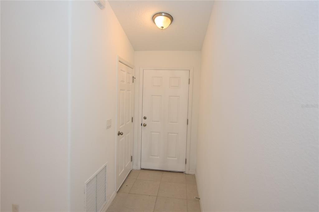 A small entryway features white walls, tile flooring, a ceiling light, and two white doors — 77 SEA TRAIL, PALM COAST, FL