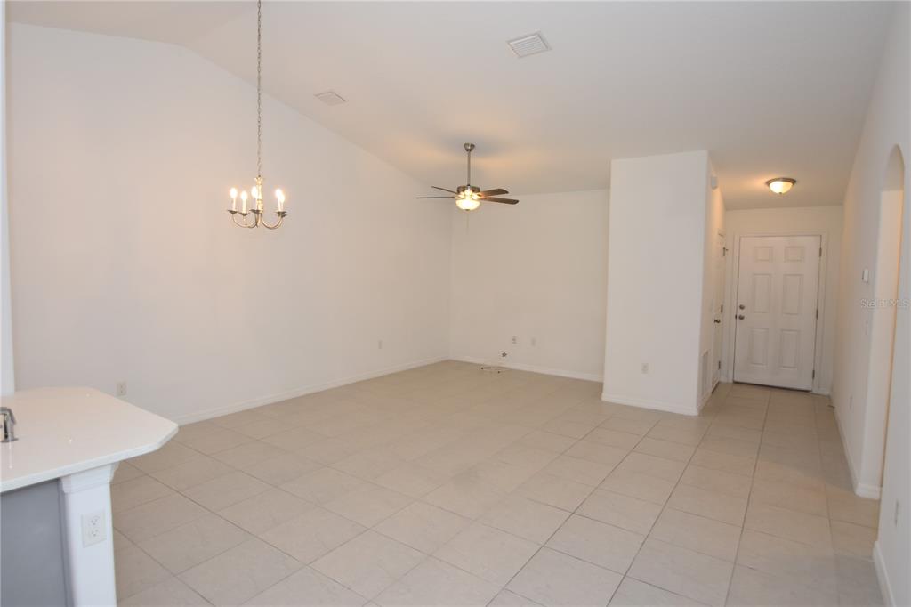 An open-concept living area features vaulted ceilings, tile flooring, a ceiling fan, and a chandelier — 77 SEA TRAIL, PALM COAST, FL