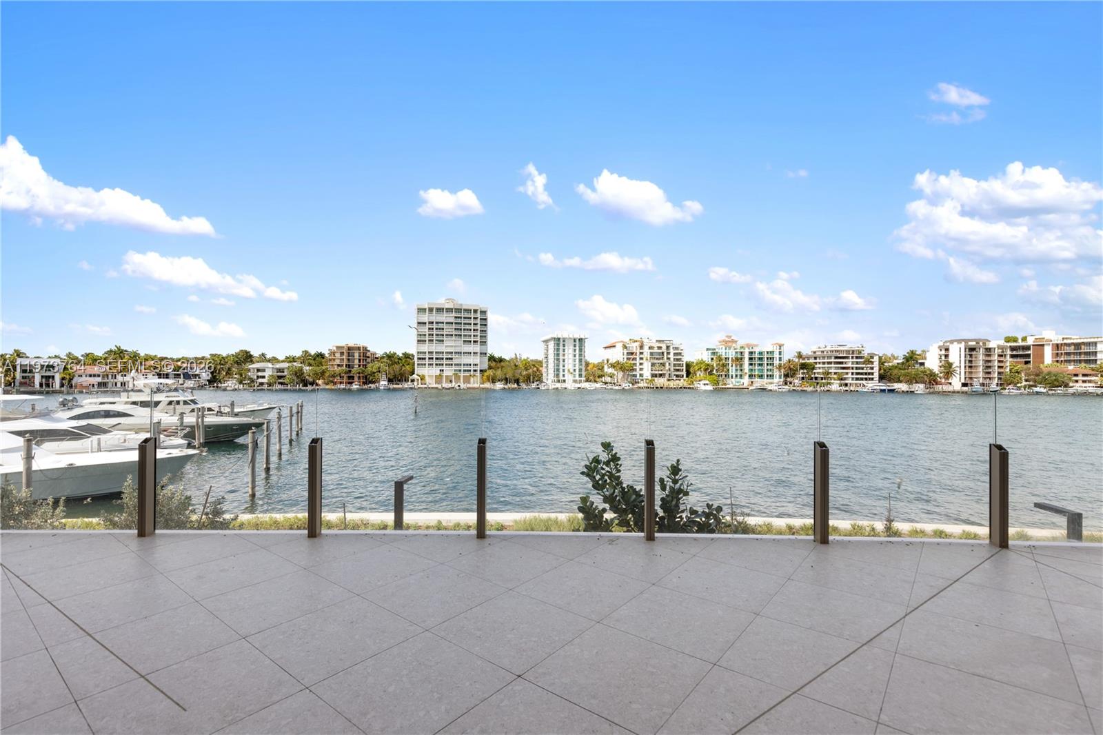 A tiled balcony overlooks a waterway with docked boats and distant apartment buildings — 5 Grove Isle Dr # S201, Miami FL 33133, MIAMI, FL