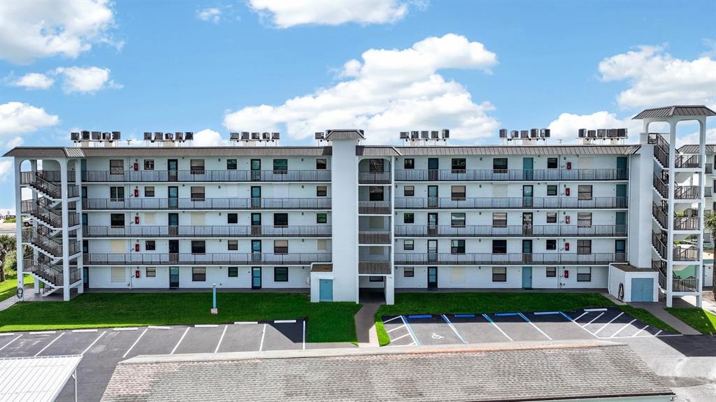 An exterior view of a multi-story apartment building with balconies and a parking lot — 3180 OCEAN SHORE BOULEVARD UNIT 510, ORMOND BEACH, FL