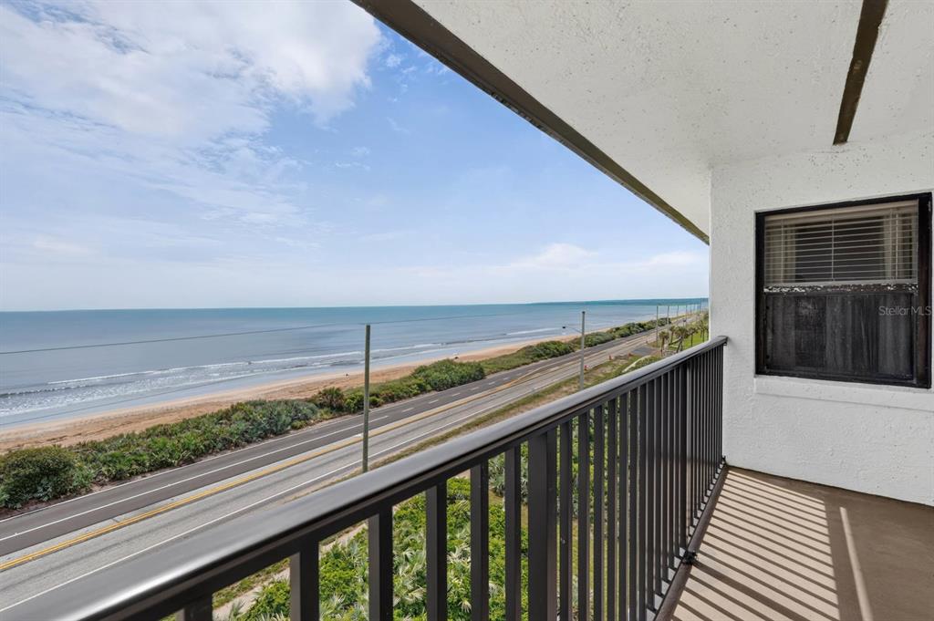A balcony with a black metal railing overlooks a coastal road and the ocean — 3180 OCEAN SHORE BOULEVARD UNIT 510, ORMOND BEACH, FL