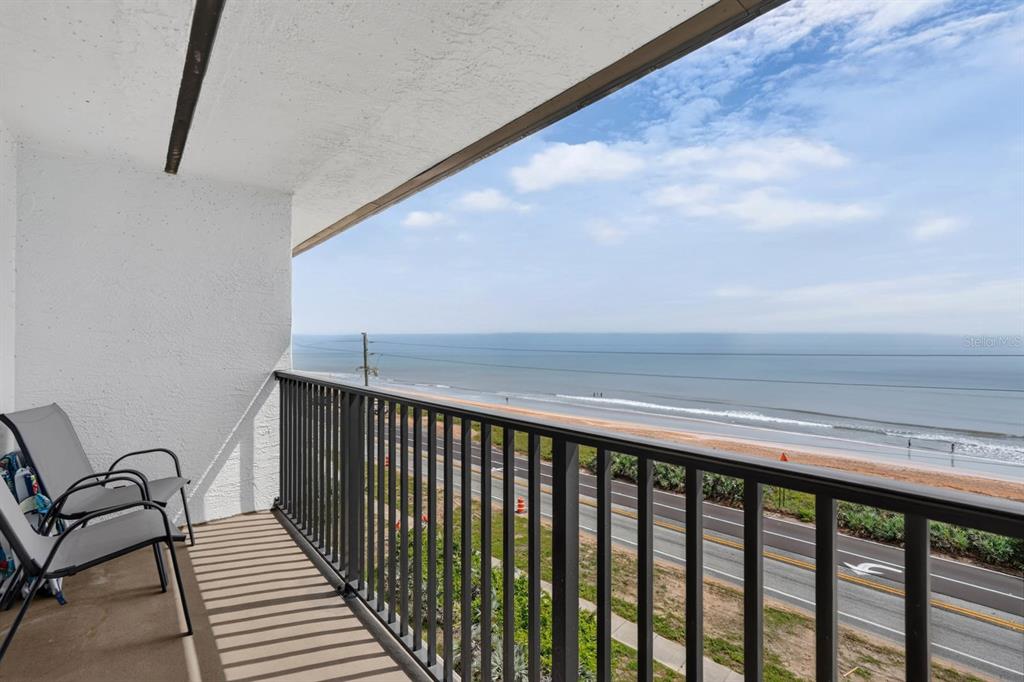 A balcony with two chairs overlooks a coastal road and the ocean — 3180 OCEAN SHORE BOULEVARD UNIT 510, ORMOND BEACH, FL