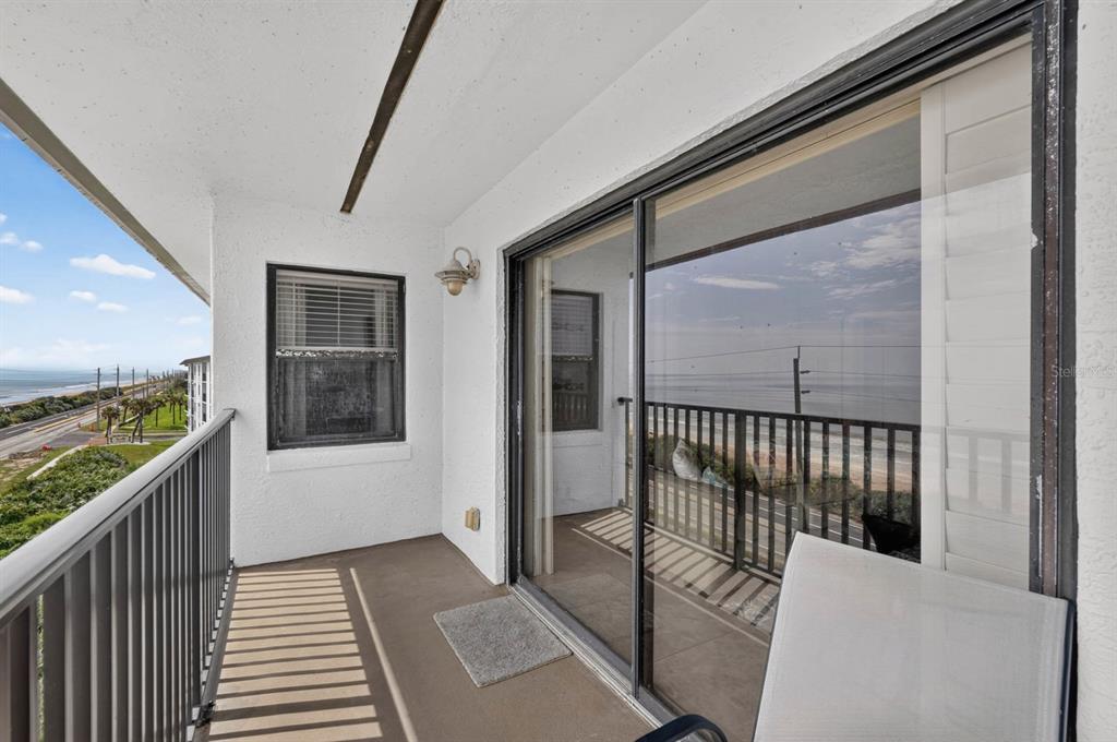 A balcony with a metal railing overlooks the ocean and a coastal road — 3180 OCEAN SHORE BOULEVARD UNIT 510, ORMOND BEACH, FL