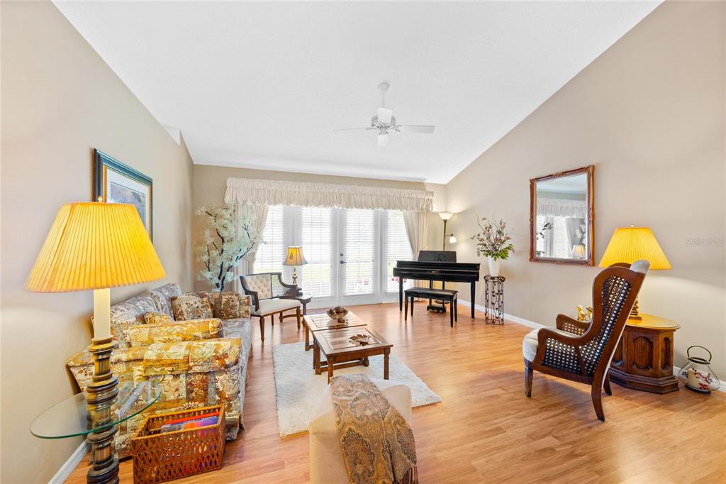 A living room features a piano, wood-look flooring, a vaulted ceiling, and a patterned sofa — 638 WHITE RIVER DRIVE, ORLANDO, FL