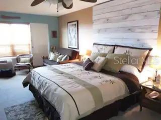 A bedroom features a large bed with a white shiplap accent wall and a sofa — 3727 S ATLANTIC AVENUE UNIT 3150, DAYTONA BEACH, FL