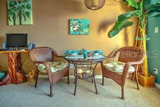 A dining area features a round wicker table with two matching chairs and a computer desk — 3727 S ATLANTIC AVENUE UNIT 3150, DAYTONA BEACH, FL