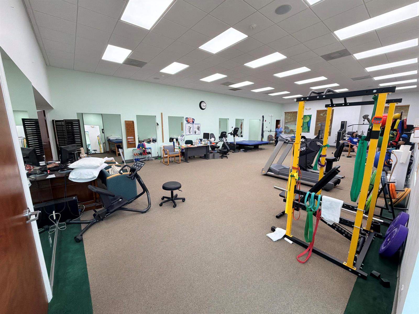 A physical therapy clinic features exercise equipment, a squat rack, desks, and carpeted flooring — 5055 S Congress Avenue # 304, Atlantis FL 33461, ATLANTIS, FL