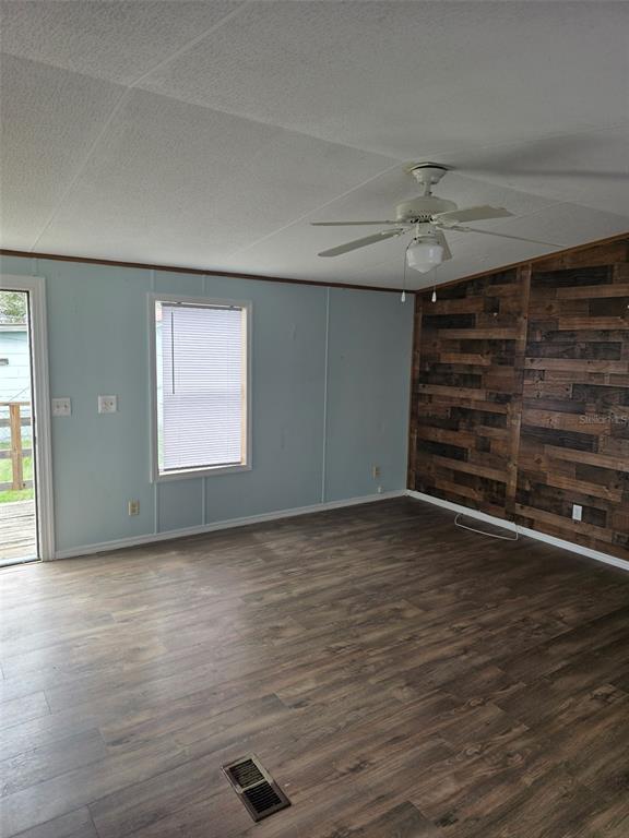 A room with light blue walls, a wood-plank accent wall, and wood-look flooring — 2544 EL DORADO AVENUE, AVON PARK, FL
