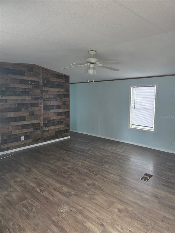 A living room features wood-look flooring, a ceiling fan, and an accent wall with wood planks — 2544 EL DORADO AVENUE, AVON PARK, FL