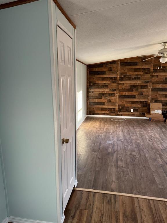 A room with wood-look flooring and a wood-plank accent wall features a white closet door — 2544 EL DORADO AVENUE, AVON PARK, FL