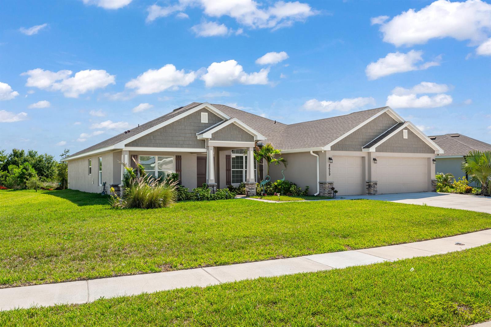 A single-story suburban house with a tan exterior, gray shingled roof, and a two-car garage — 8659 Waterstone Boulevard, Fort Pierce FL 34951, FORT PIERCE, FL