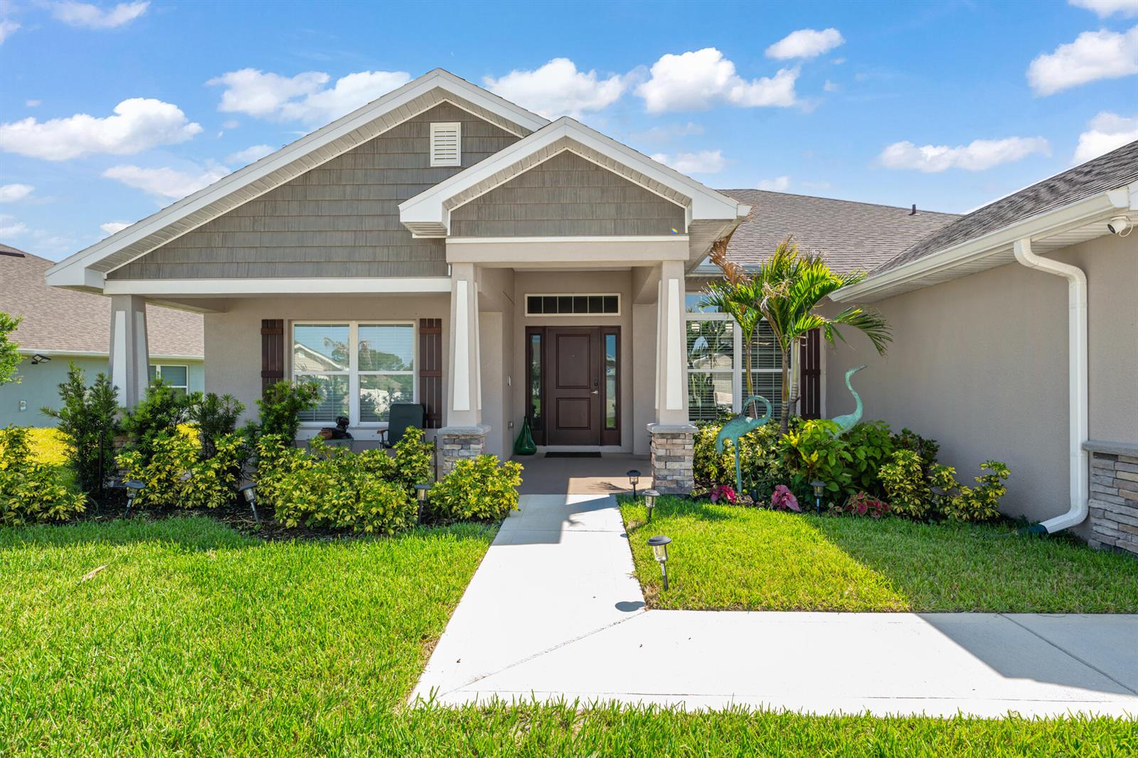 A single-story house with a gray shingle roof, tan stucco walls, and a front walkway — 8659 Waterstone Boulevard, Fort Pierce FL 34951, FORT PIERCE, FL