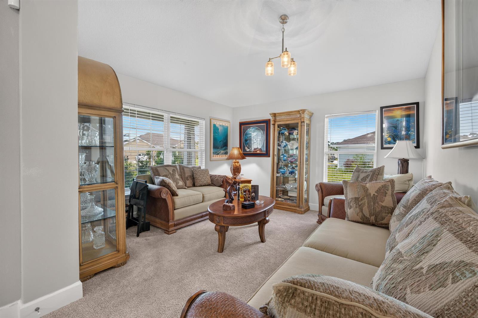 A living room features two sofas, a coffee table, two glass display cabinets, and carpeting — 8659 Waterstone Boulevard, Fort Pierce FL 34951, FORT PIERCE, FL