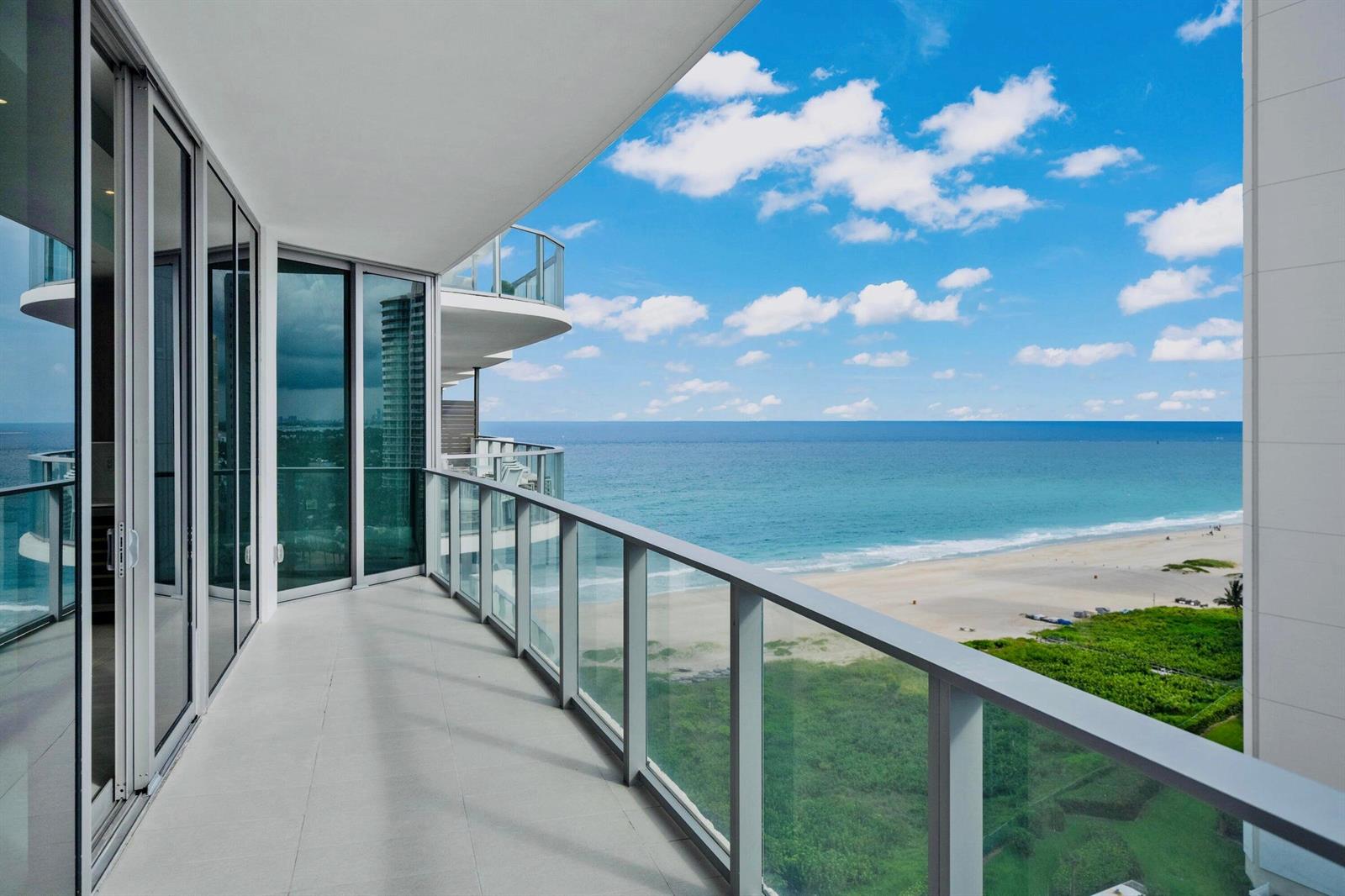 A modern balcony with glass railings overlooks a sandy beach and the ocean — 3100 N Ocean Drive # 1608, Singer Island FL 33404, SINGER ISLAND, FL