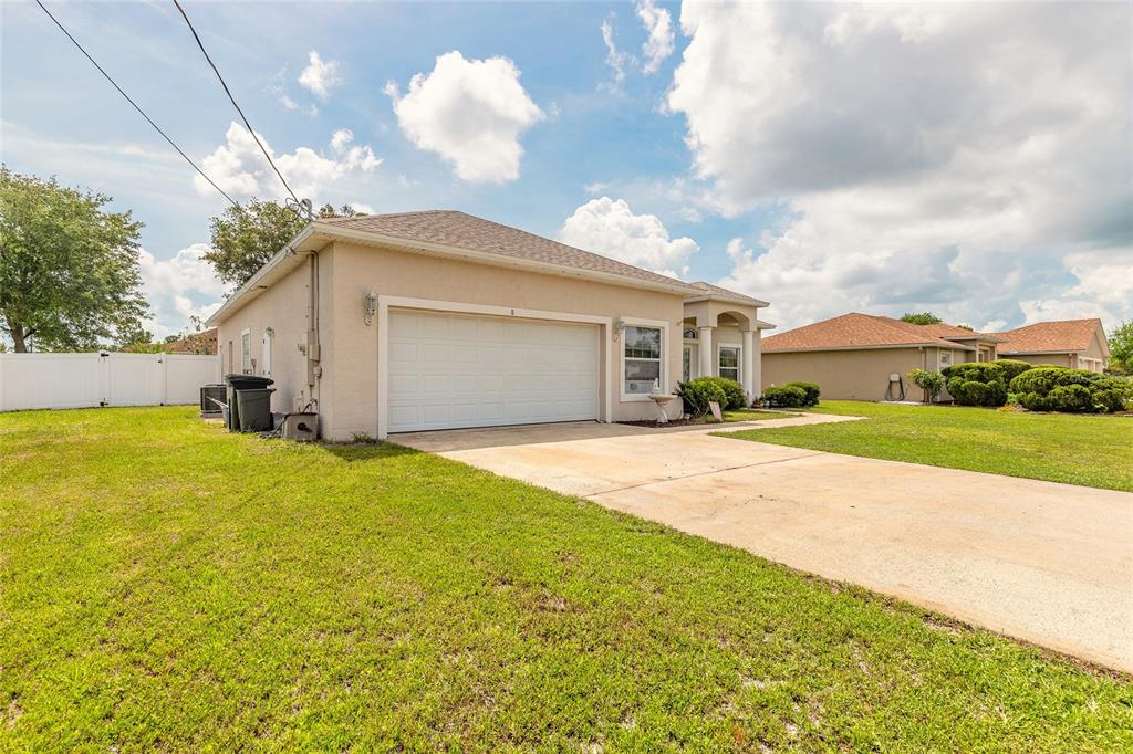 A single-story house with a beige stucco exterior, a two-car garage, and a concrete driveway — 8 LAMOYNE LANE, PALM COAST, FL